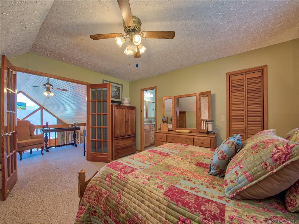 464 Bent Tree Road Maggie Valley, NC 28751 - Photo 10 of 38 a spacious bedroom with a bed a chandelier and a dresser
