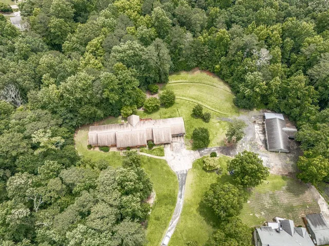 an aerial view of a house with a yard and trees all around