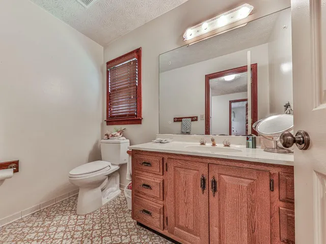 a spacious bedroom with a bed a dresser and a chandelier