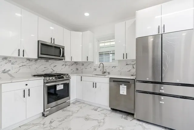 a kitchen with stainless steel appliances granite countertop a refrigerator stove a sink and white cabinets