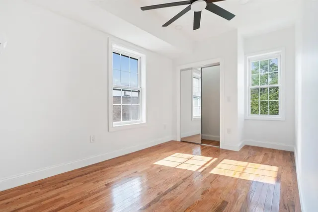 a view of empty room with wooden floor and fan