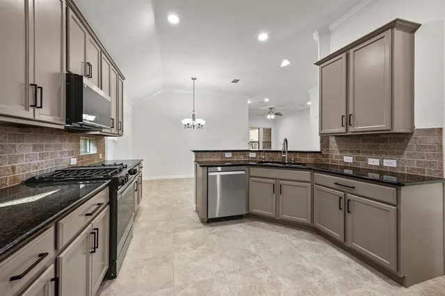 a kitchen with stainless steel appliances granite countertop a stove a sink and a microwave