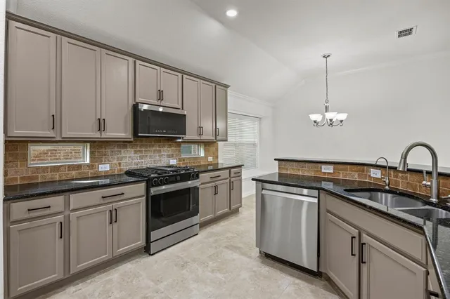 a kitchen with stainless steel appliances granite countertop a sink a stove and cabinets