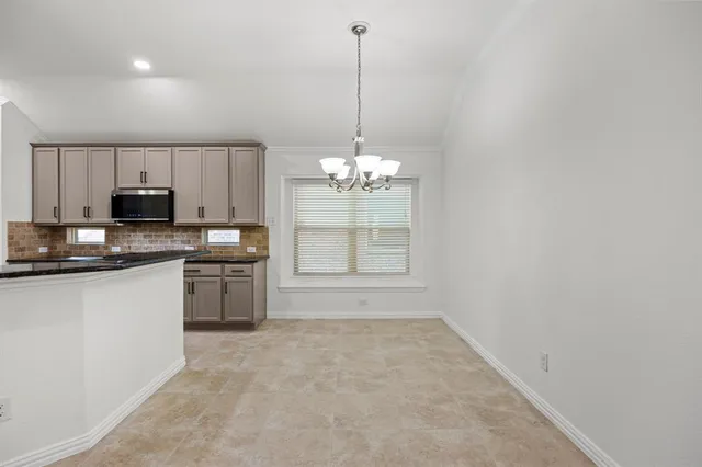a open kitchen with kitchen island granite countertop a stove a sink a window and white cabinets