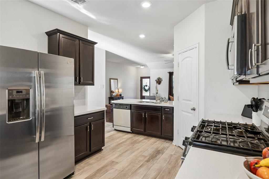 406 Madrone Lane Princeton, TX 75407 - Photo 9 of 30 Kitchen featuring wood-finish flooring, dark wood cabinetry, light countertops, and stainless steel appliances