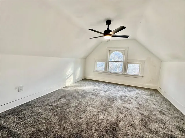 an empty room with ceiling fan and windows