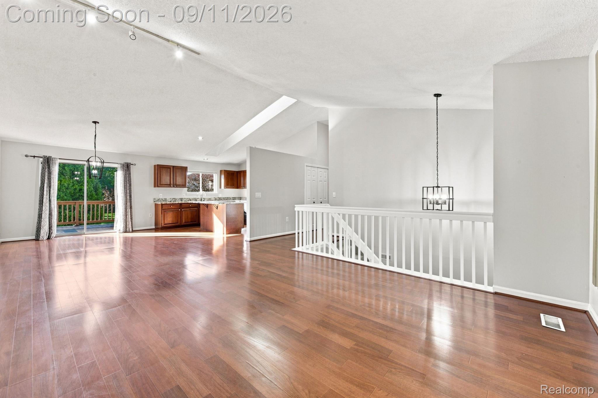 3201 Lynhurst Court Rochester, MI 48306 - Photo 10 of 43 Hardwood flooring, vaulted ceilings, track lighting, sliding glass door, and a built-in kitchen area with cabinetry