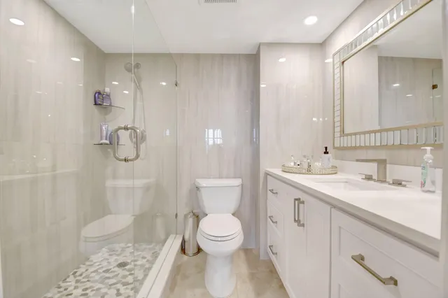 a bathroom with a granite countertop sink a toilet and shower
