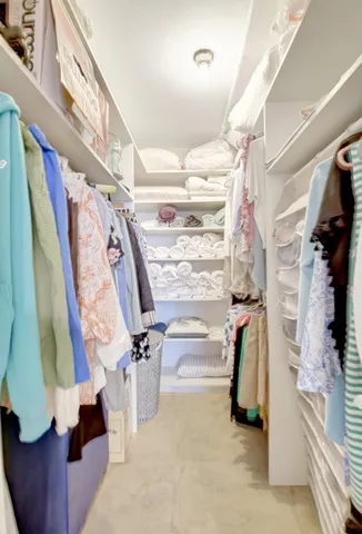 a view of walk in closet with clothes and shoes