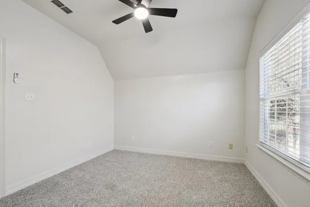 an empty room with a window and a fan