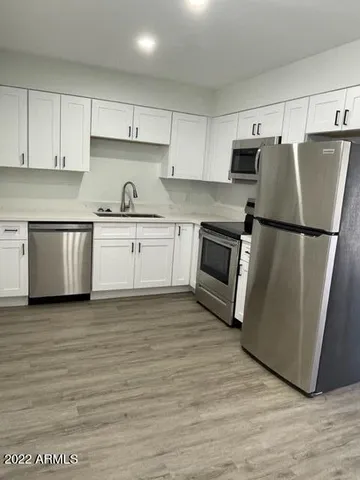 a kitchen with granite countertop a refrigerator stove top oven and sink