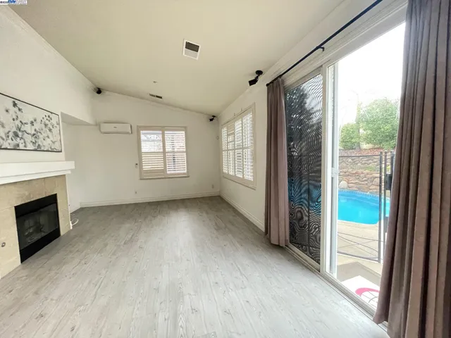 a view of an empty room with a fireplace and a window