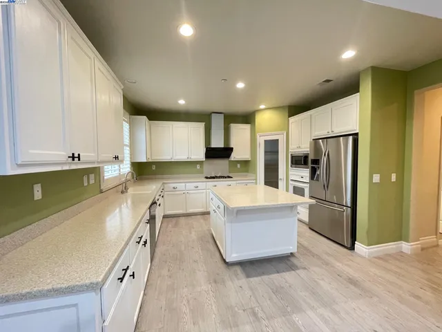 a large kitchen with stainless steel appliances granite countertop a refrigerator and a sink