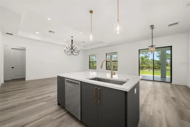 a view of a kitchen with kitchen island wooden floor stainless steel appliances and window