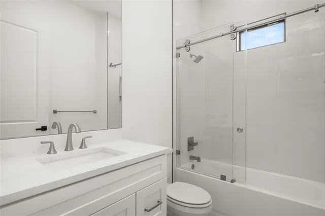 an empty room with wooden floor ceiling fan and windows