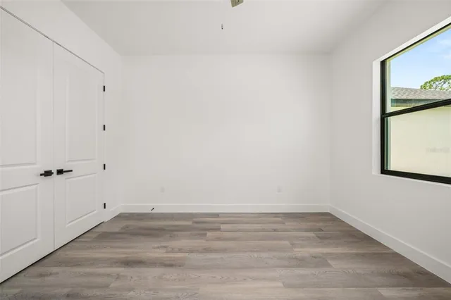 a view of empty room with wooden floor and window