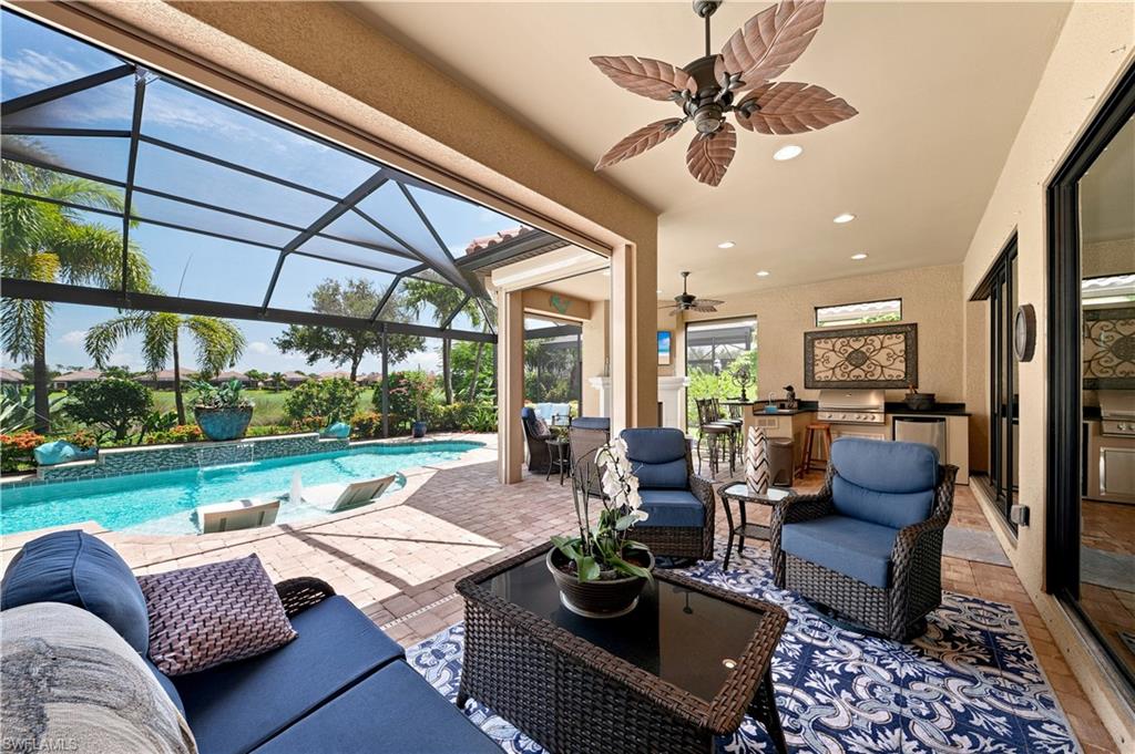 9256 Rialto Lane Naples, FL 34119 - Photo 37 of 43 Screened lanai featuring a free-form pool, integrated spa, sun shelf, brick paver decking, and lush landscaping