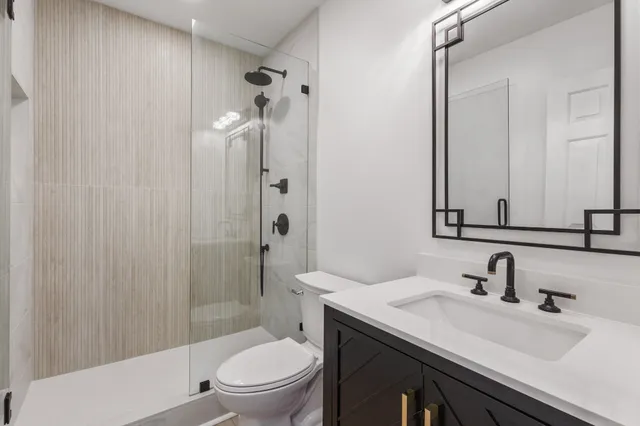 a bathroom with a sink toilet vanity and shower