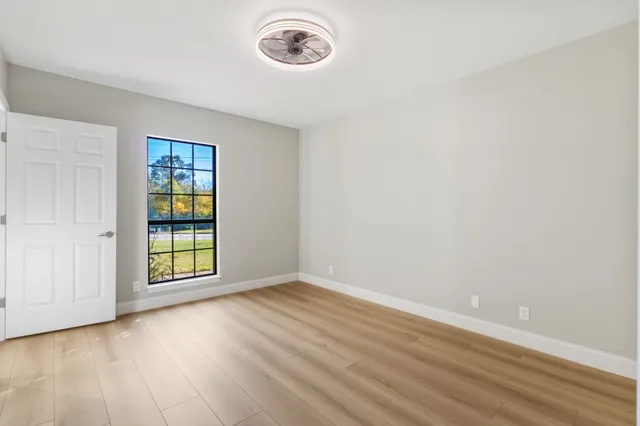 an empty room with wooden floor and windows