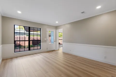 a view of an empty room with a window and wooden floor