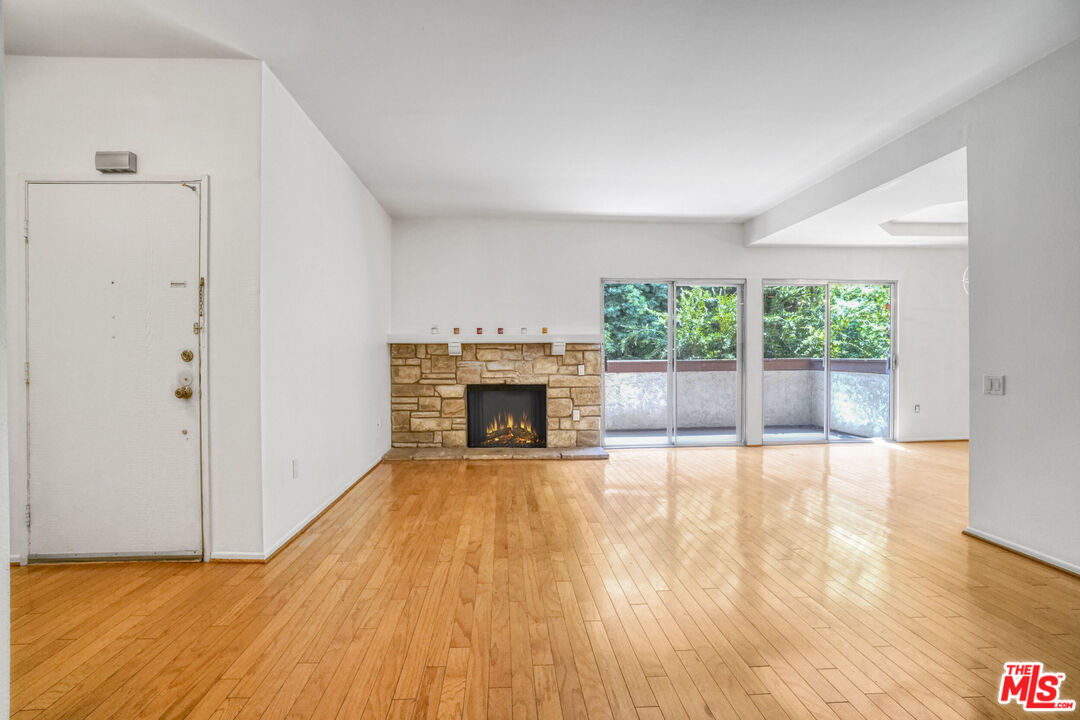 a view of empty room with wooden floor and fireplace