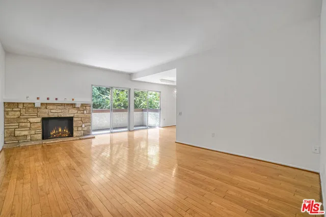 a view of empty room with wooden floor and fireplace