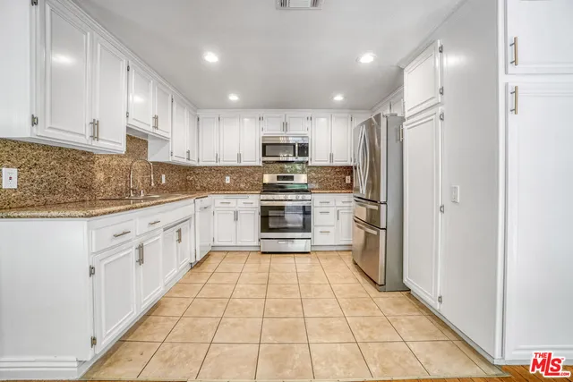a kitchen with granite countertop white cabinets stainless steel appliances and sink