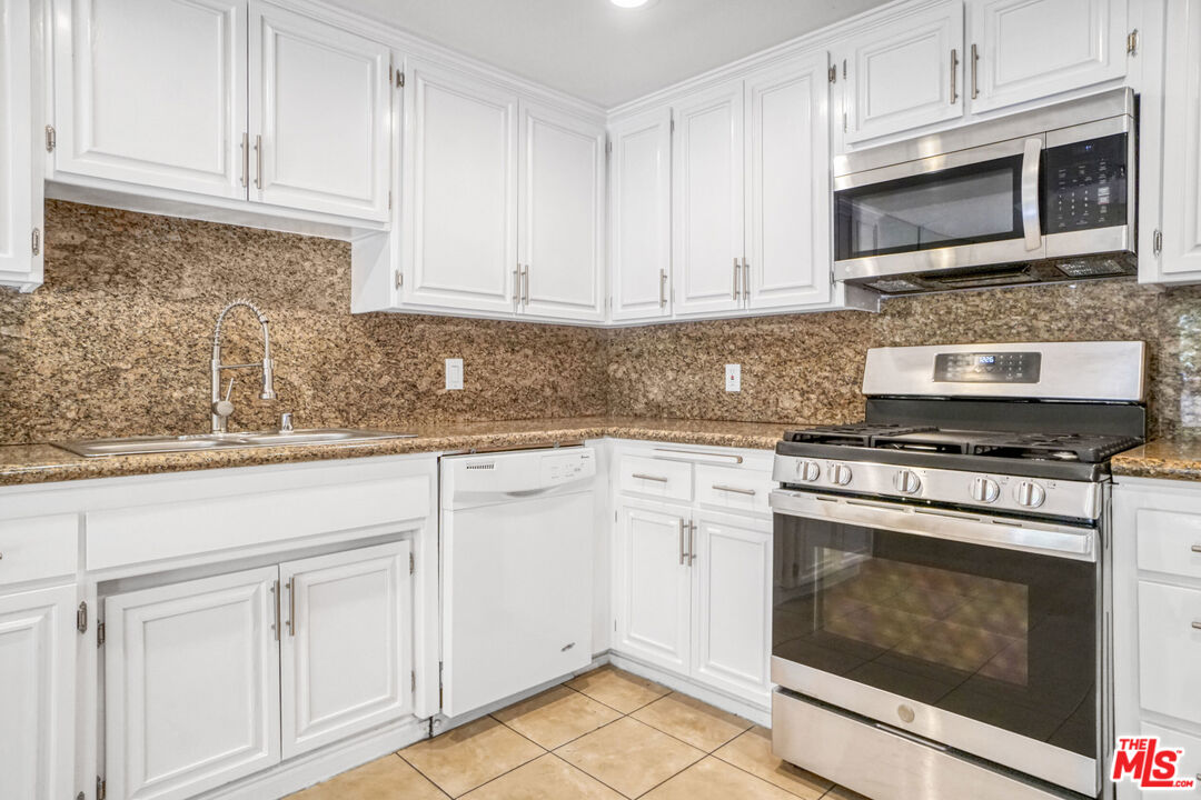 5534 Sylmar Avenue, Unit 5 Sherman Oaks, CA 91401 - Photo 9 of 33 a kitchen with granite countertop white cabinets stainless steel appliances and sink