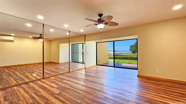 a view of empty room with wooden floor and fan