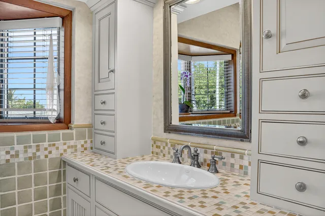 a bathroom with a granite countertop sink a mirror and shower