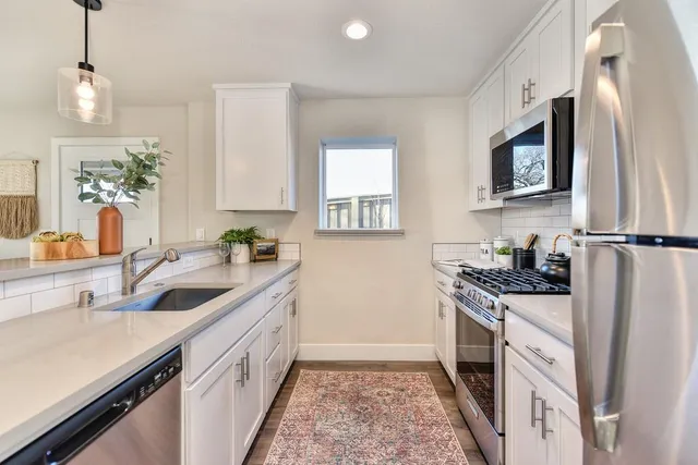 a kitchen with stainless steel appliances granite countertop a sink stove and microwave