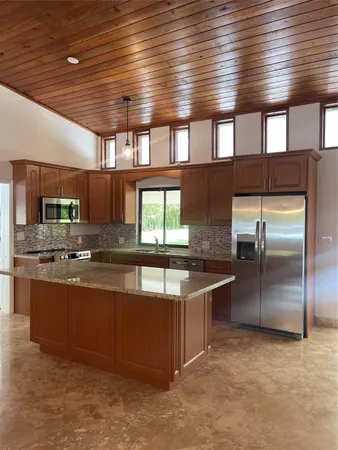 a large kitchen with stainless steel appliances wooden cabinets a stove and a refrigerator