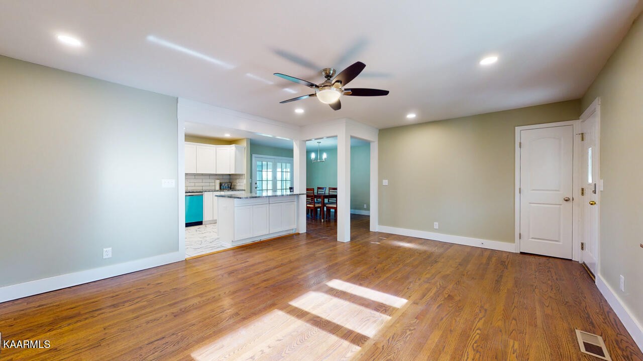 3877 Riverview Road Lenoir City, TN 37771 - Photo 11 of 47 a view of an empty room and kitchen with wooden floor and a ceiling fan