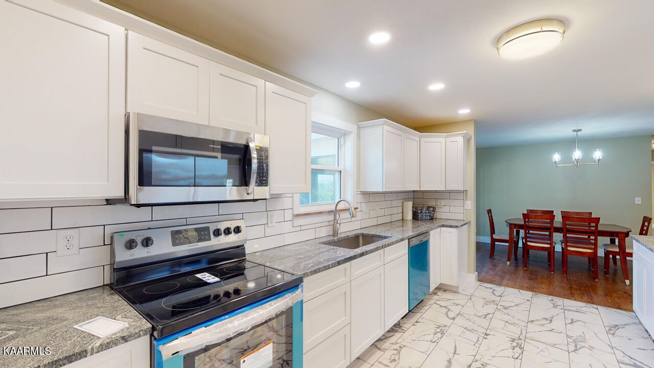 3877 Riverview Road Lenoir City, TN 37771 - Photo 14 of 47 a kitchen with stainless steel appliances a stove a sink a microwave a dining table and chairs