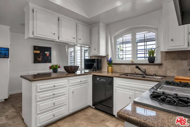 a kitchen with white cabinets and appliances