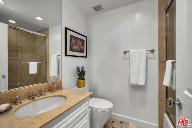 a bathroom with a granite countertop sink toilet and a mirror