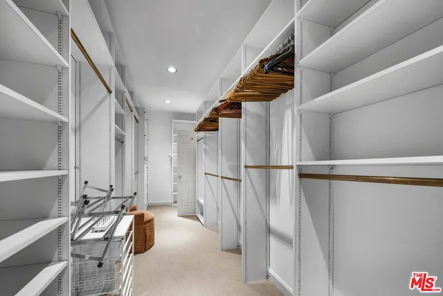 a view of walk in closet with clothes and shoes