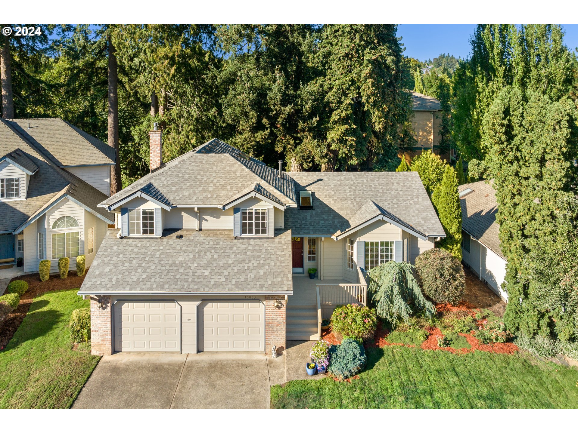 a view of a white house next to a yard with large trees