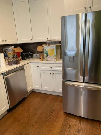 a kitchen with stainless steel appliances granite countertop a refrigerator a sink and white cabinets