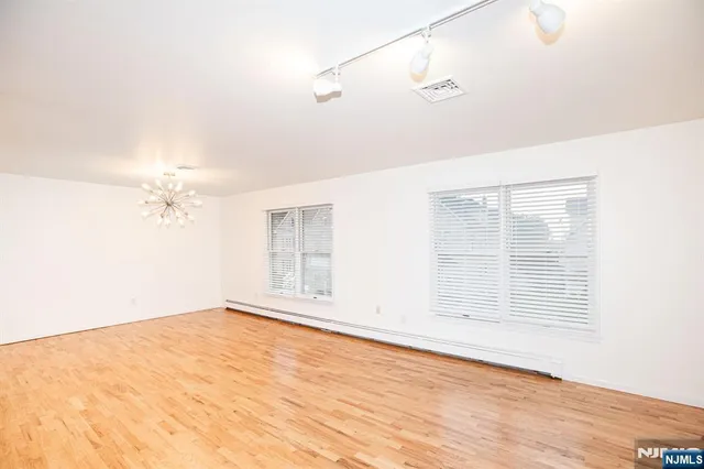 an empty room with wooden floor fan and windows