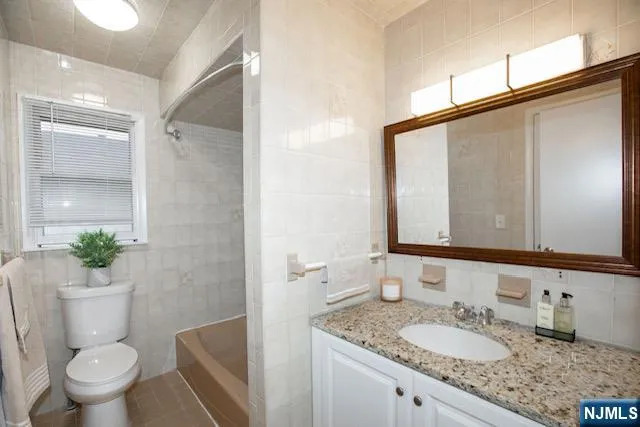 a bathroom with a granite countertop sink a mirror and a toilet