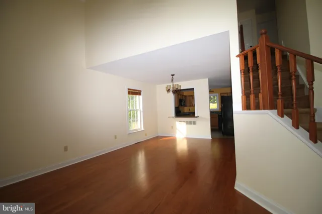 a view of a hallway with wooden floor and a kitchen
