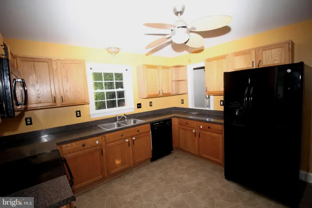 a kitchen with a chandelier stainless steel appliances granite countertop cabinets and a window