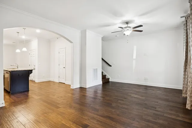 a view of an empty room with wooden floor and a ceiling fan