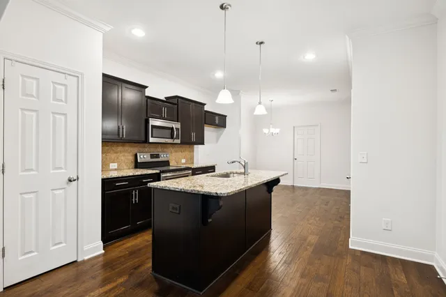 a kitchen with stainless steel appliances granite countertop a sink stove and wooden floor
