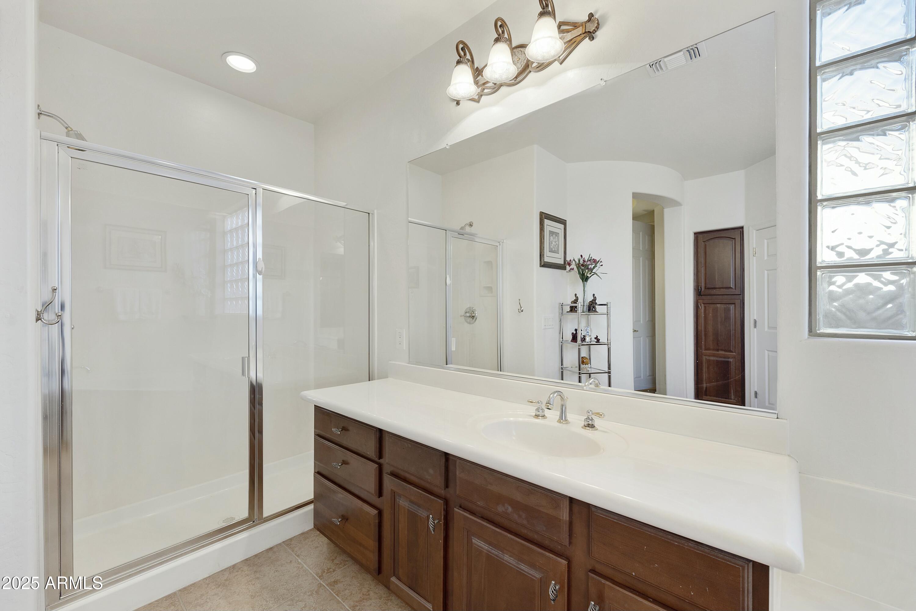 4615 West Corral Road Laveen, AZ 85339 - Photo 22 of 48 a bathroom with a double vanity sink a large mirror and a shower