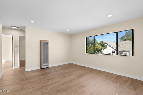 an empty room with wooden floor and windows