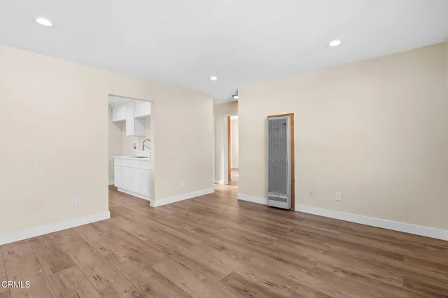 a view of an empty room with wooden floor and closet