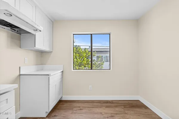 a view of a kitchen with white cabinets and a window