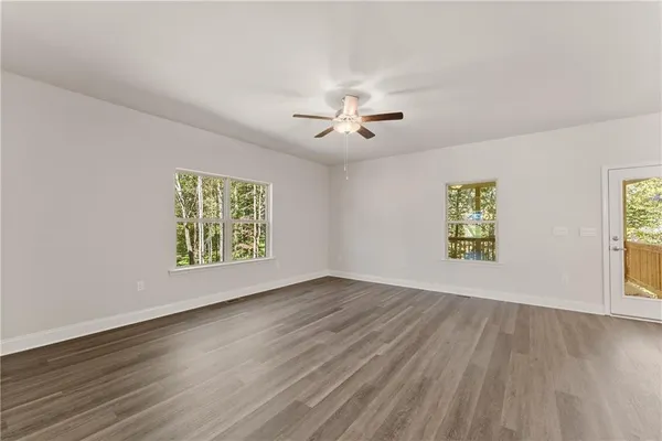 a view of an empty room with a window and wooden floor